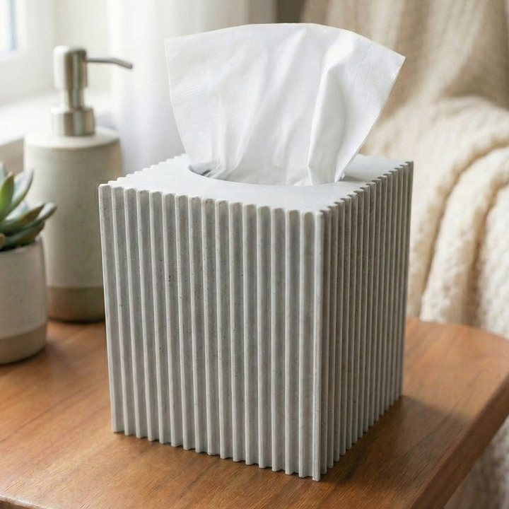 Tissue box on a wooden table with a plant and soap dispenser in the background