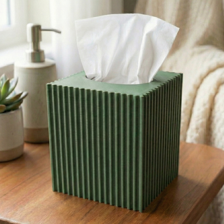 Green striped tissue box on a wooden table with a plant and soap dispenser in the background.