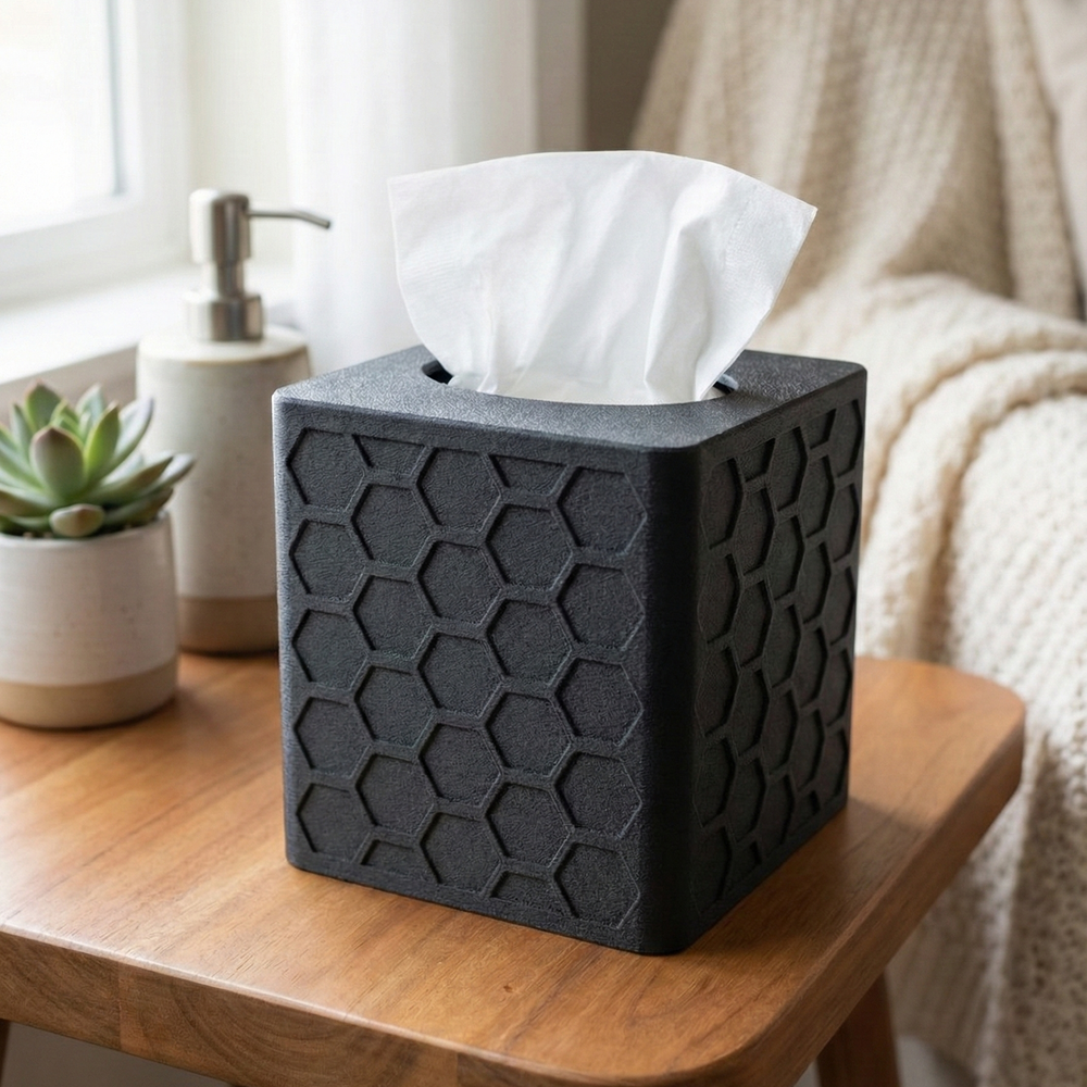 Black hexagonal tissue box on a wooden table with a white tissue peeking out, in a home setting.